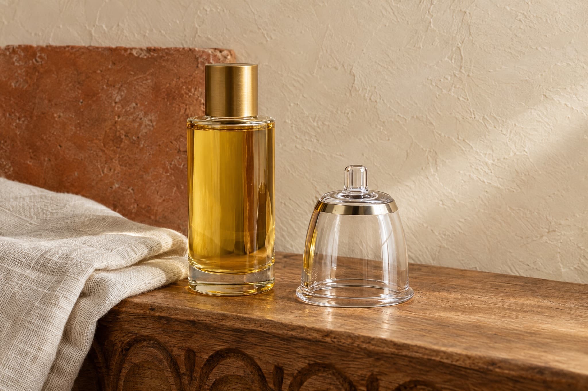 A bottle of body oil with a brass cap and a clear vacuum cup on a carved cedar ledge
